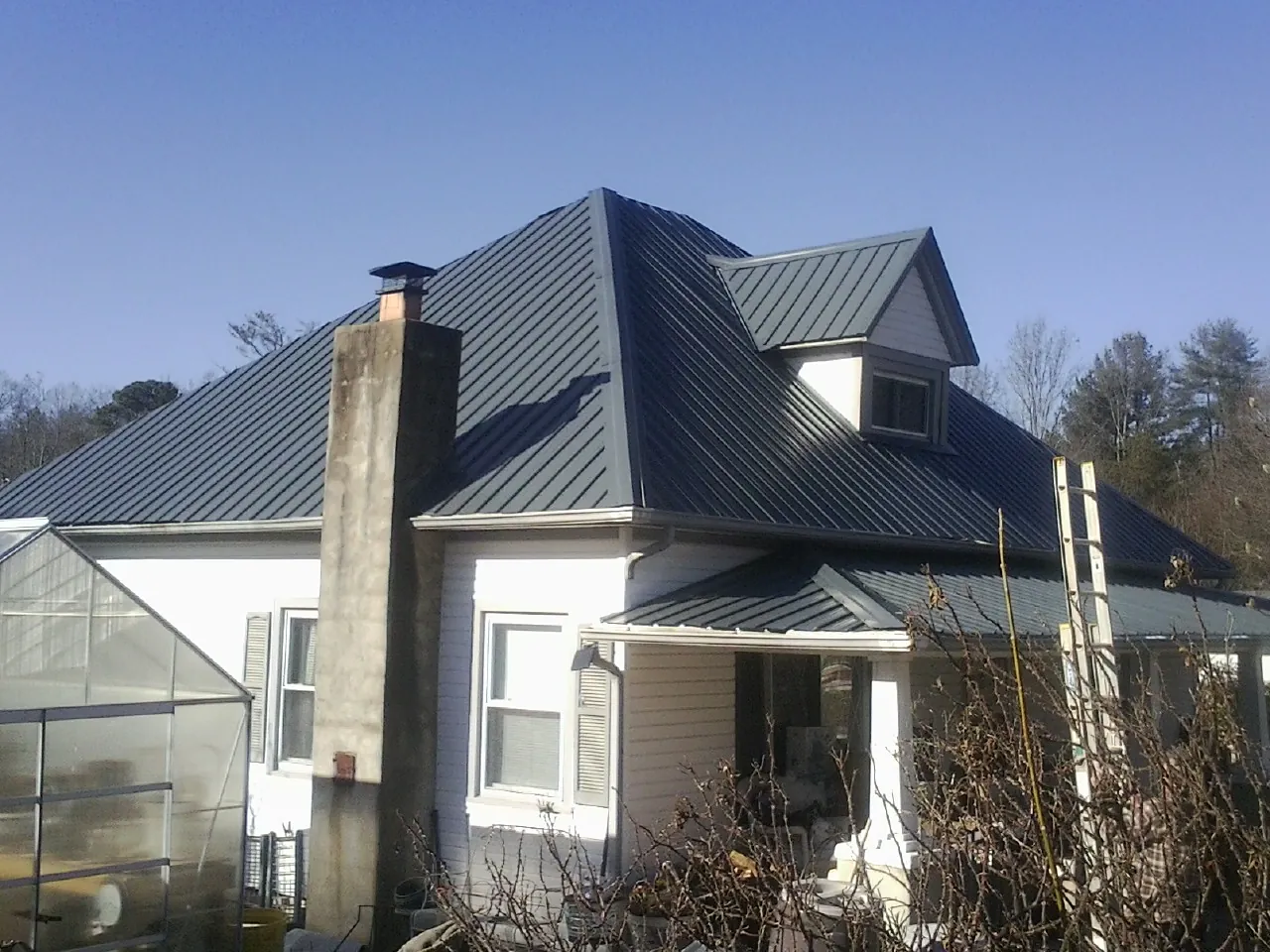 Dark blue standing seam metal roof on a white farmhouse with dormer — Slate & Tile Roof Repair by Roofing Brothers in Webster City