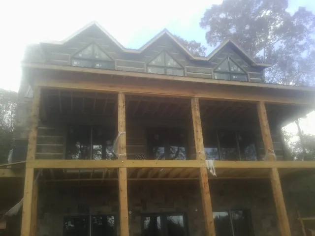 Dormers and porch framing on a large log home under construction — Roof Coating work by our crew in Webster City