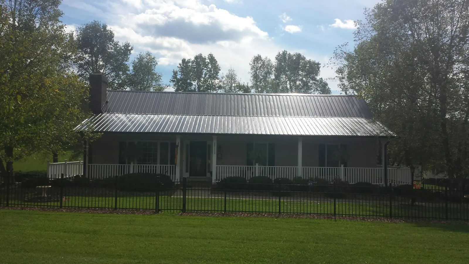 Gray metal roof on a brick ranch with a full width front porch — Gutter Guard Installation work by our crew in Webster City