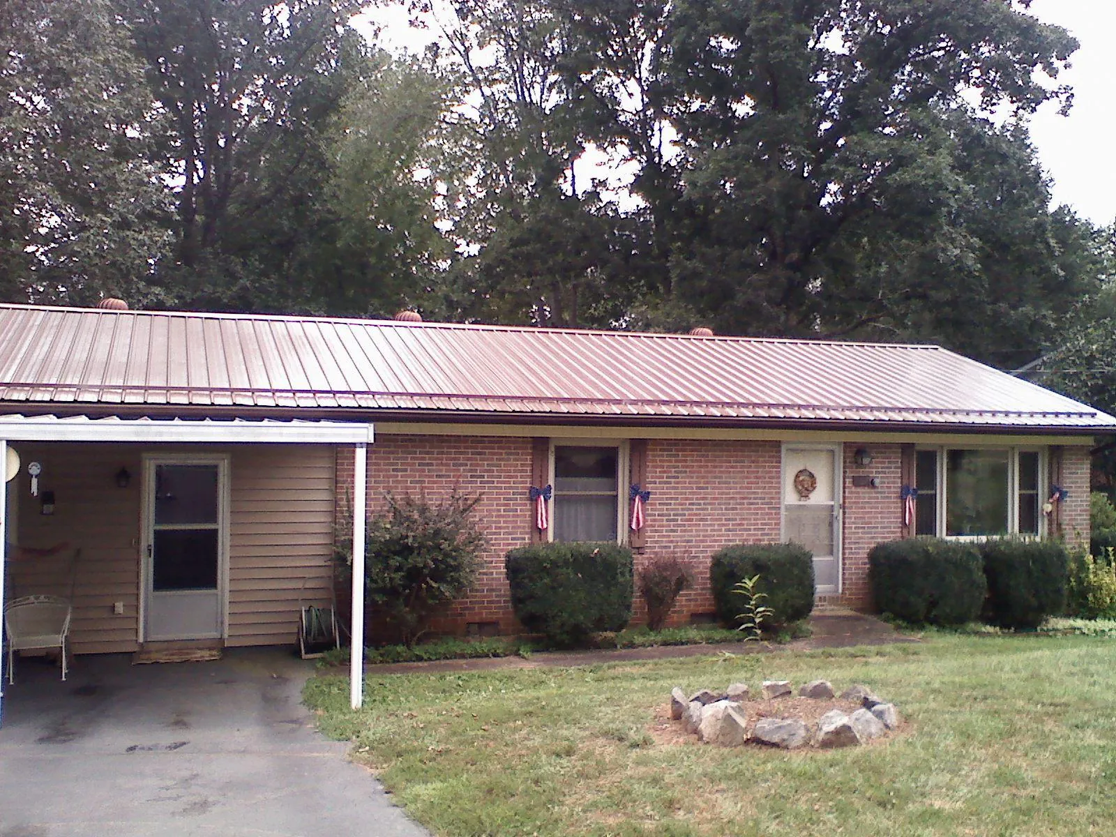 Bronze metal roof and carport on a brick ranch home — Roof Repair work by our crew in Webster City