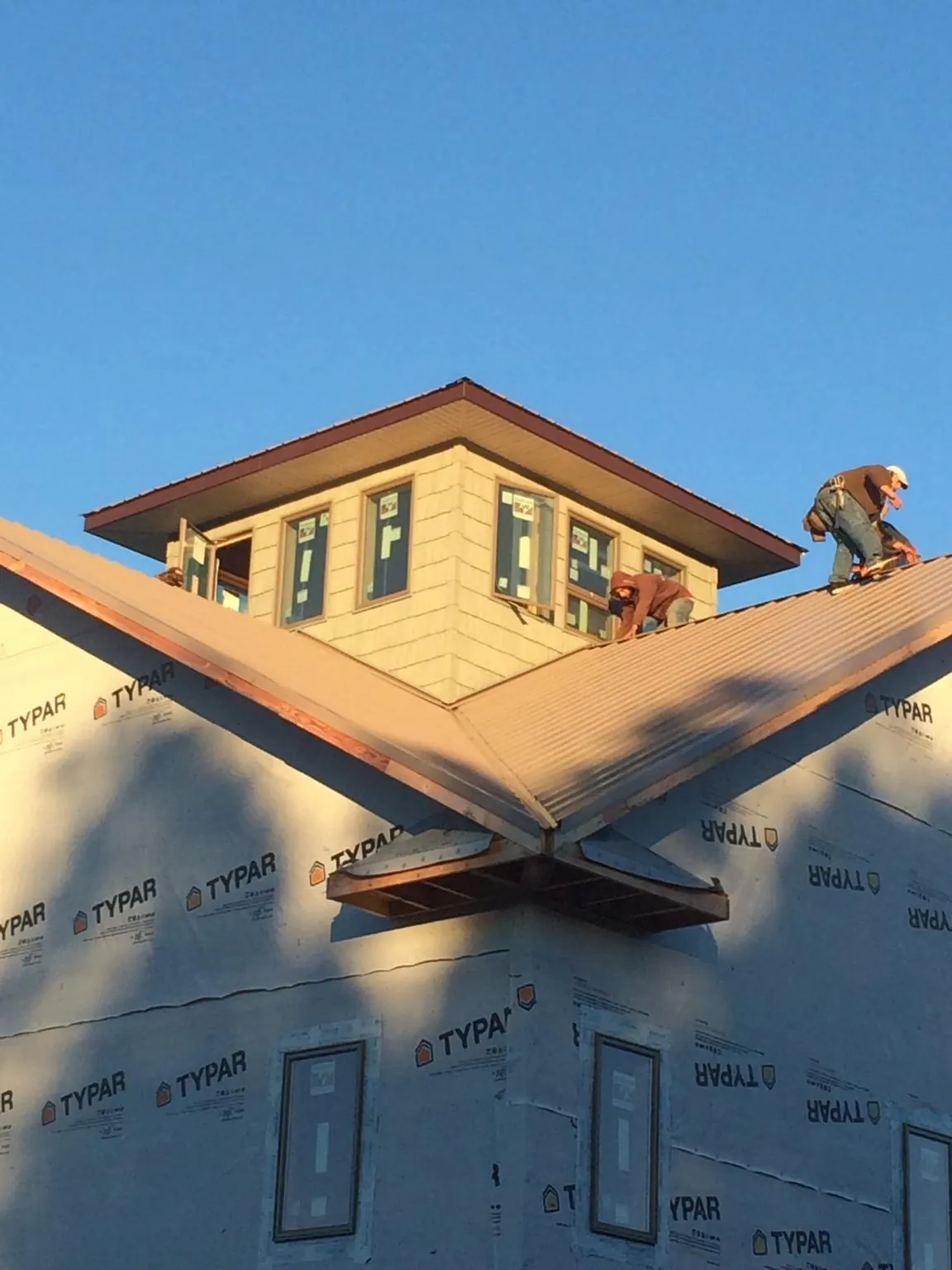 Roofers working around a rooftop cupola on a new metal roof at sunset — Roof Waterproofing in Webster City by Roofing Brothers
